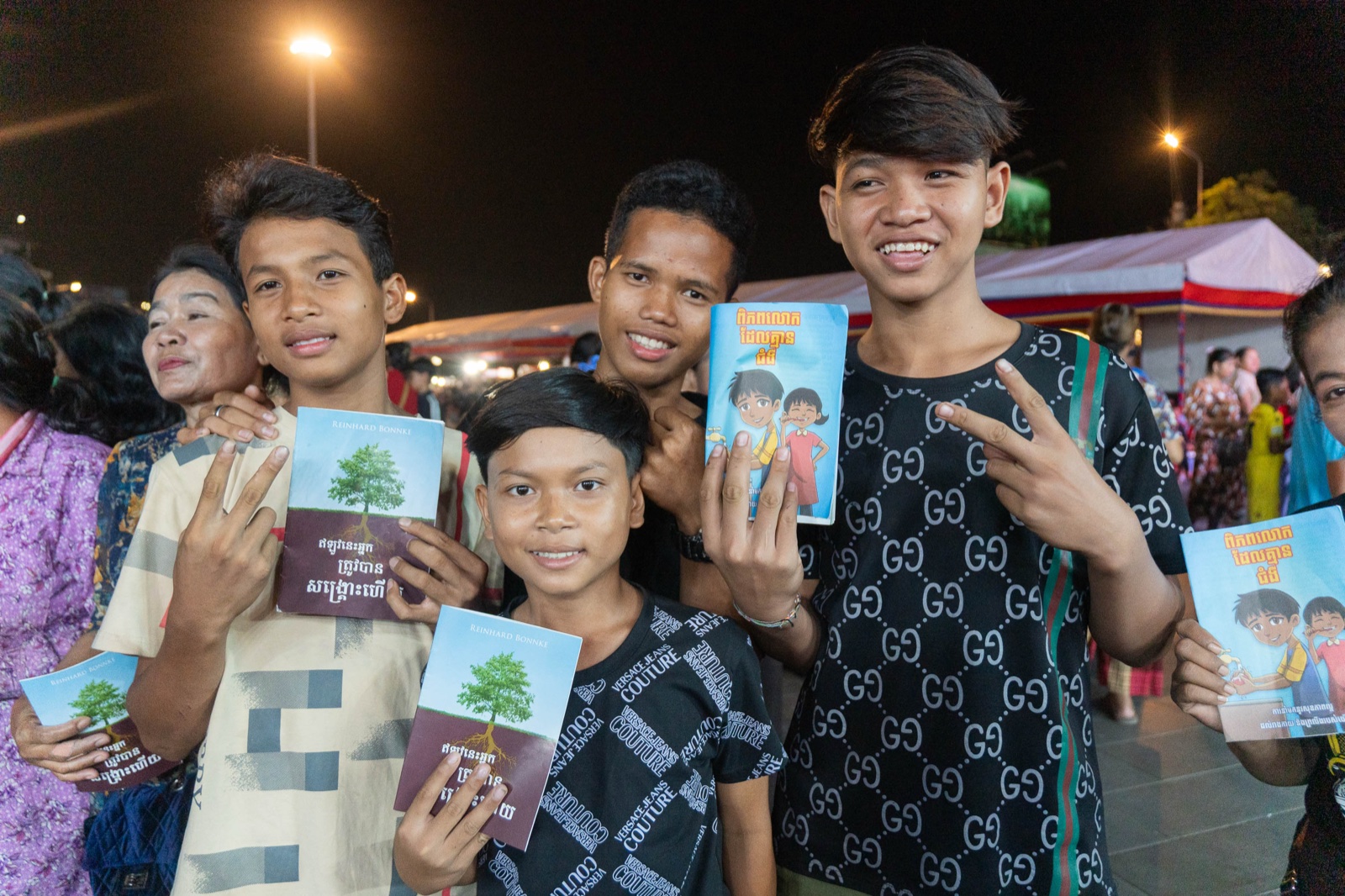 Young people holding gospel booklets at the Kandal crusade, 2026